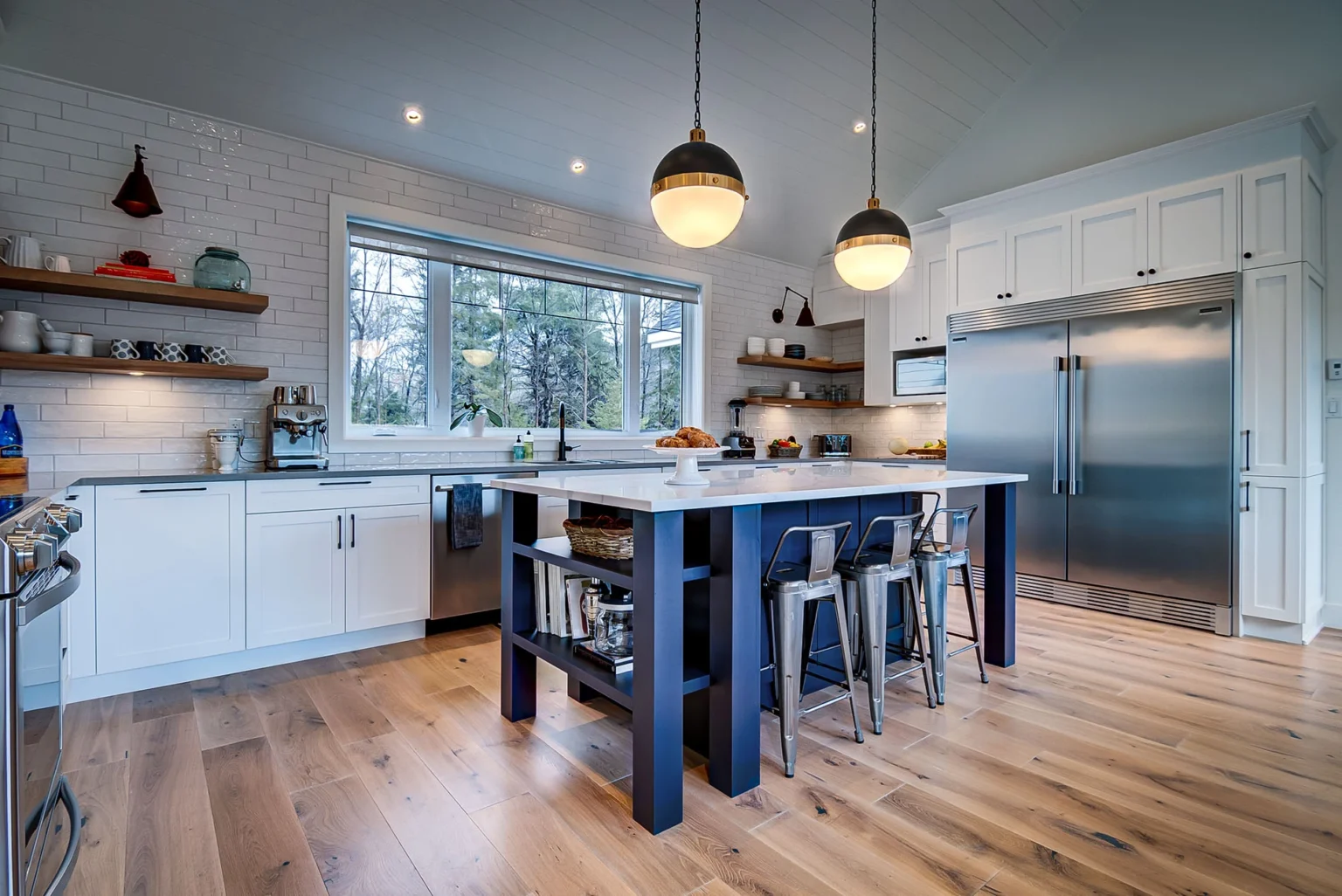 Îlot de cuisine bleu avec places assises et luminaires suspendus