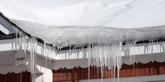 Accumulation de glace et glaçons au bord d’une toiture