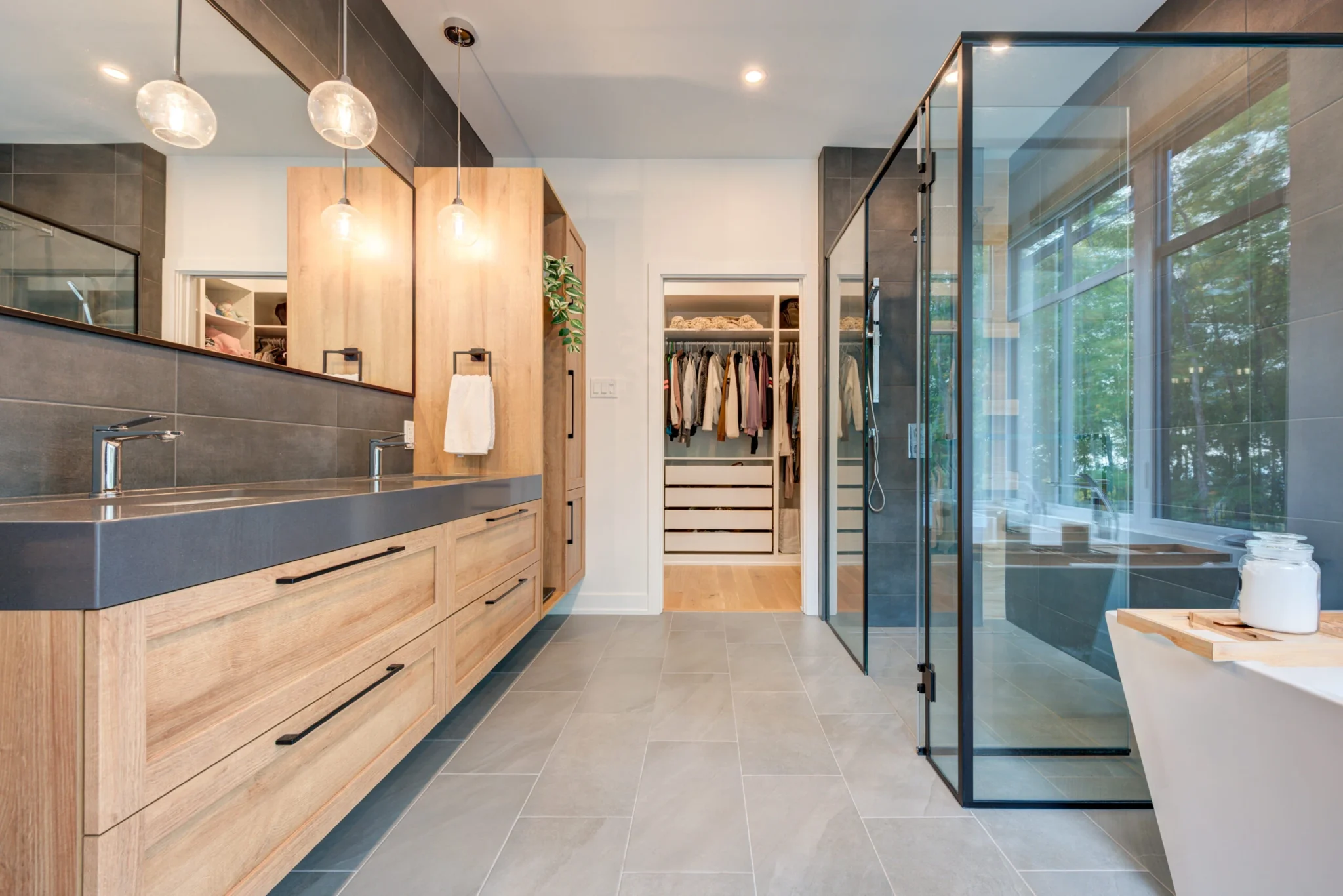 Long wood vanity beside a walk-in glass shower
