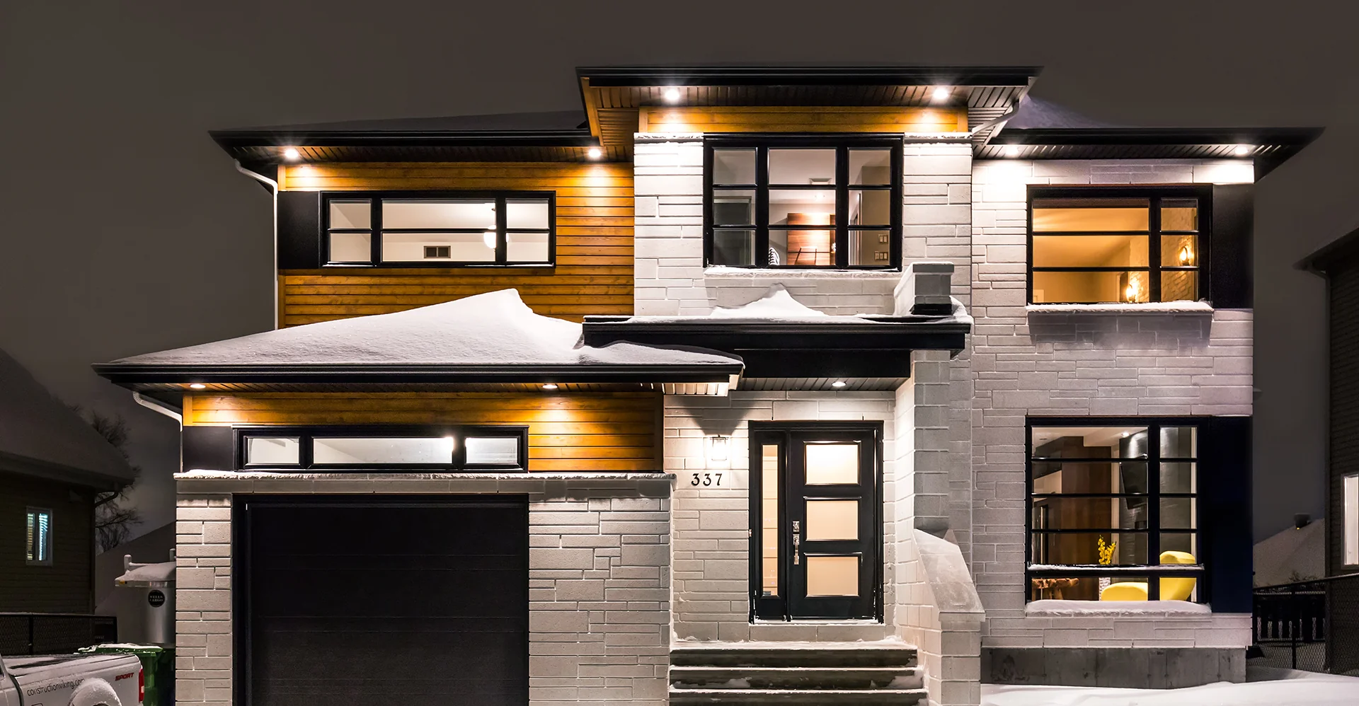 Maison contemporaine Viking avec façade en pierre blanche et bois, éclairée en soirée