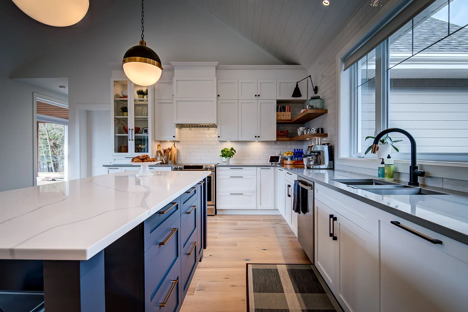 White kitchen with a blue island and large windows