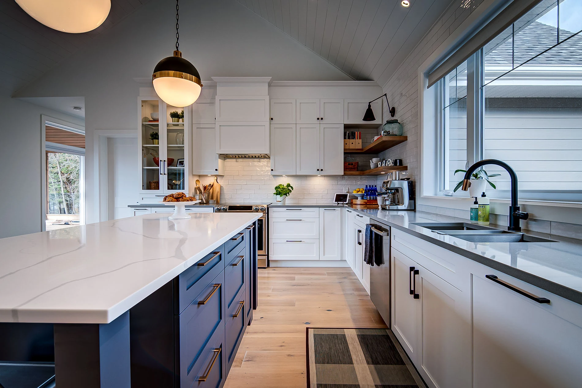 Cuisine blanche avec îlot bleu et grandes fenêtres